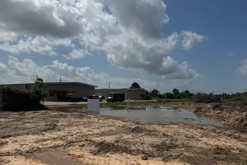 A cleared lot stripped to subgrade in front of an existing building