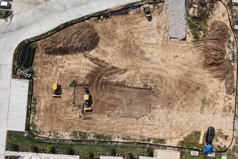 Overhead view of a fenced pad site with stacked pipe staged along one edge