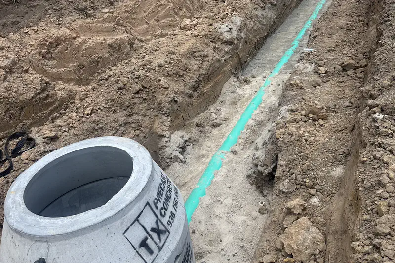 A precast concrete structure set beside a bedded pipe run in an open trench