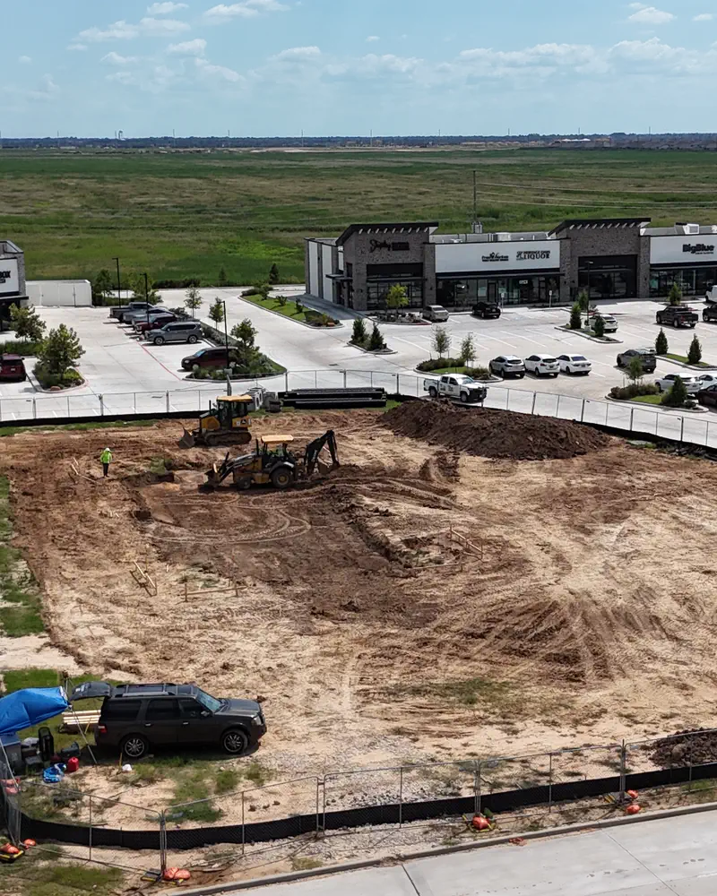 An aerial view of a pad being set out beside a completed, planted development