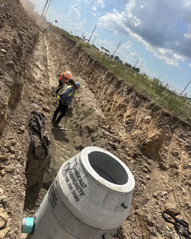 A crew member setting line beside a precast structure in an open trench